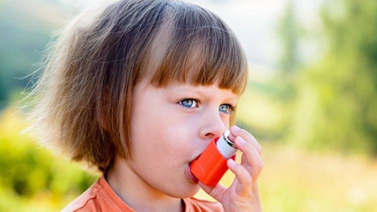 Little girl using inhaler on a sunny day