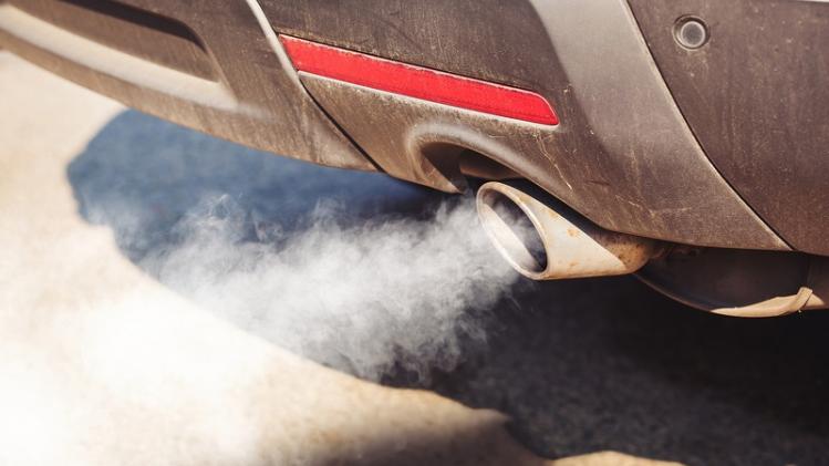 air pollution from dirty and aged vehicle exhaust pipe on road