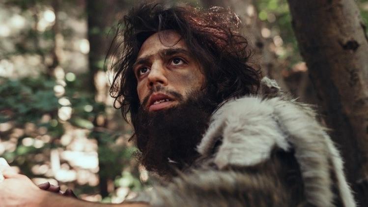 Close-up Portrait of Primeval Caveman Wearing Animal Skin and Fur Hunting with a Stone Tipped Spear in the Prehistoric Forest. Prehistoric Neanderthal Hunter Ready to Throw Spear in the Jungle