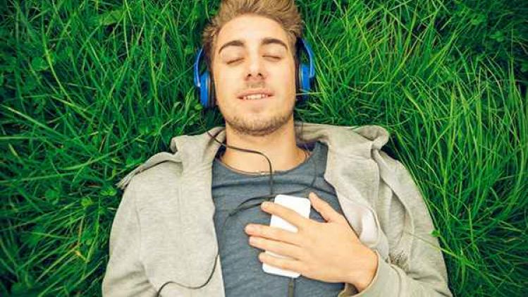Young man with headphones lying down in the grass