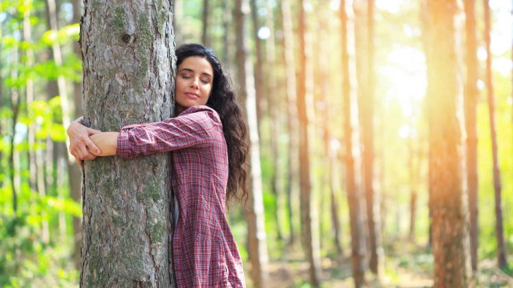 Young woman hugging tree in woodland
