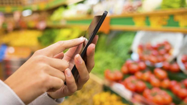 Woman using mobile phone while shopping in supermarket