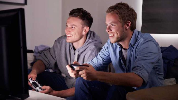 Two Young Men Playing Video Game At Home